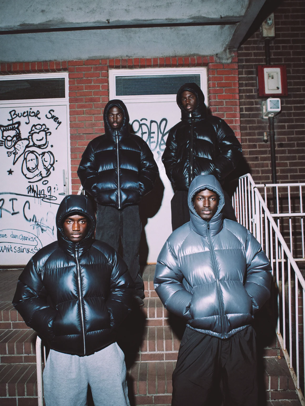 A group in black and silver puffer jackets on brick steps under direct flash